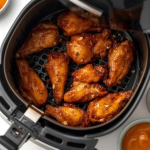 Golden crispy chicken wings in an air fryer basket.