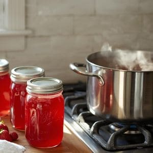 Small decorative canning jars of strawberry syrup tied with rustic twine and a handwritten label.