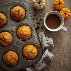 Freshly baked pumpkin muffins on a rustic wooden table with fall leaves