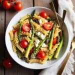 A bowl of asparagus pasta salad garnished with fresh basil