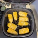Fresh corn on the cob cooking inside an air fryer basket
