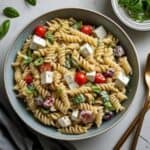 Colorful Greek pasta salad with tomatoes, cucumbers, olives, and feta cheese in a bowl