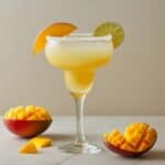 Glass of vibrant mango margarita with lime wedge and salt rim
