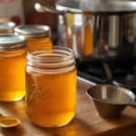 Jars of homemade apple jelly with fresh apples and canning supplies