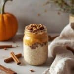 jar of creamy overnight pumpkin oats topped with pecans and cinnamon