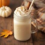 Pumpkin spice milkshake next to a slice of pumpkin pie