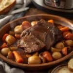 Pot roast served on a platter with potatoes and carrots.