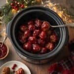 Crockpot of cranberry meatballs garnished with fresh herbs