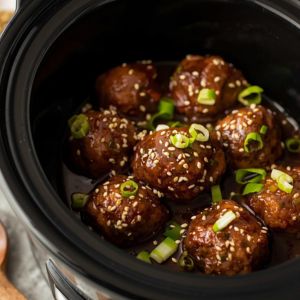 Several Mongolian meatballs on toothpicks arranged neatly on a white serving platter.