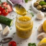 Jar of homemade Greek salad dressing with fresh herbs